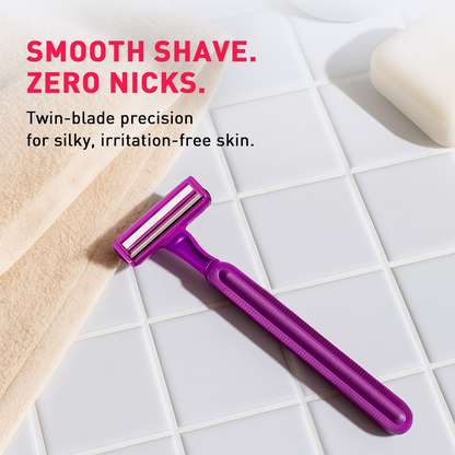 Purple razor on a tiled bathroom floor with text about smooth shaving and zero nicks.