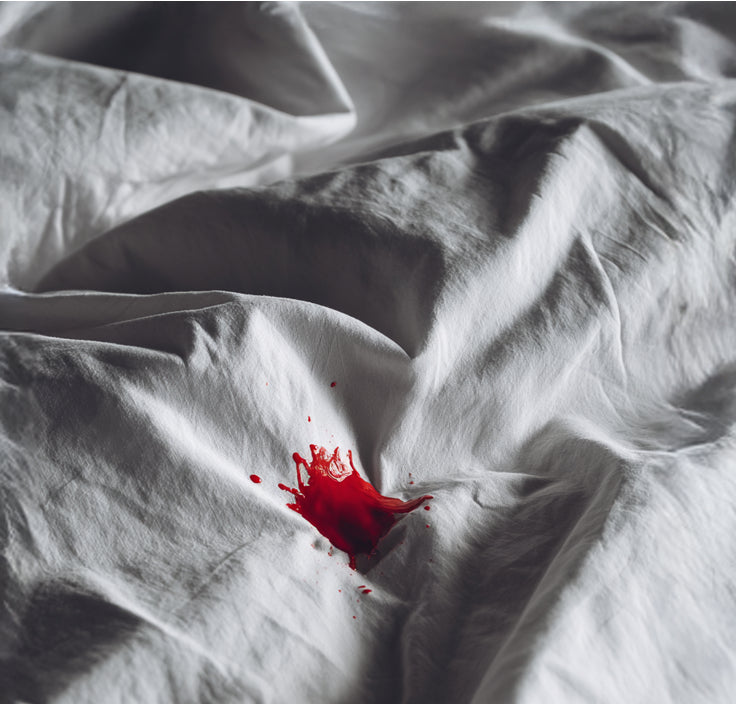 Red liquid stain on white bedding